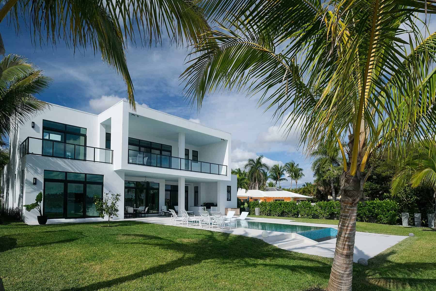 Modern beachfront house with pool and palm trees.