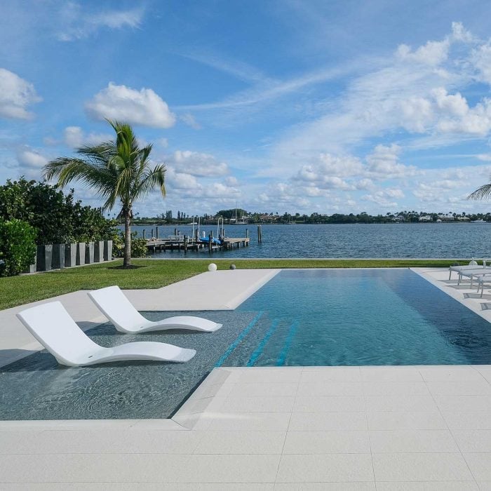 Tropical poolside view with palm trees and ocean.
