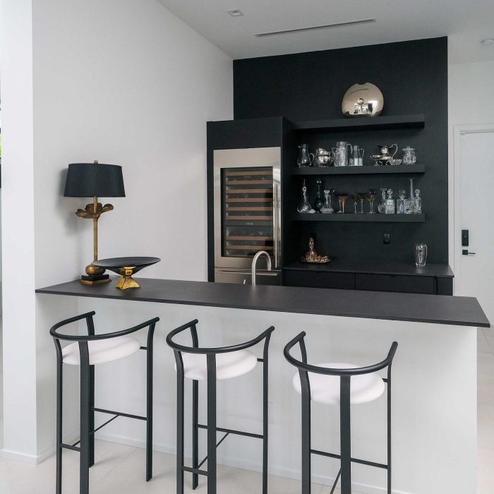 Modern home bar with stools and black countertop.