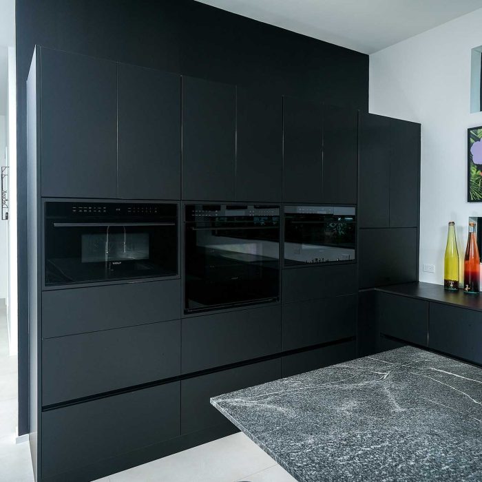 Modern kitchen with sleek black cabinets and art.