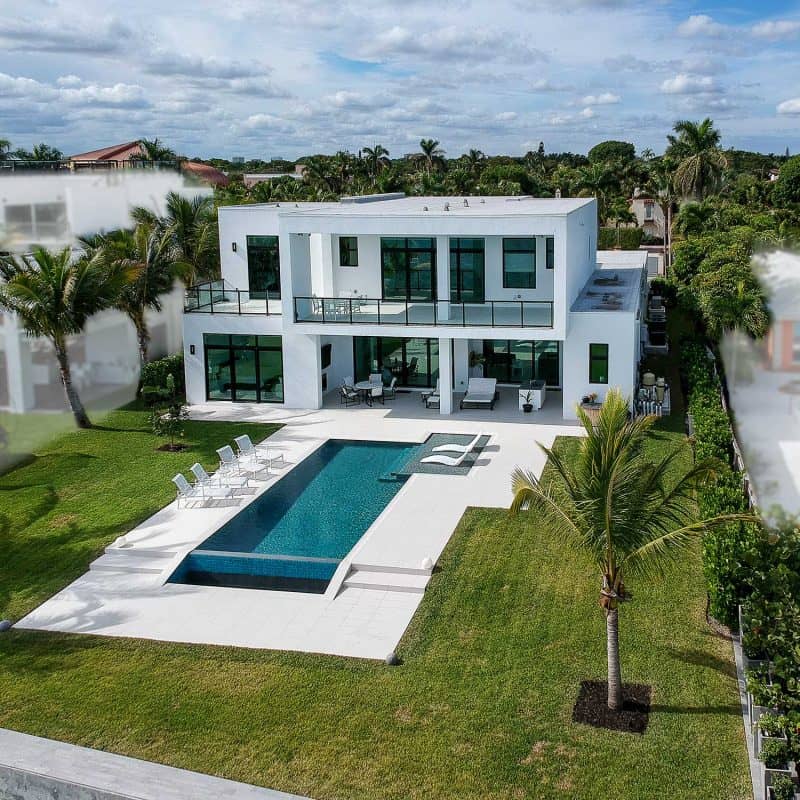Modern luxury home with pool and lush landscape.