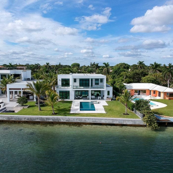 Luxury waterfront mansion with pool and palm trees