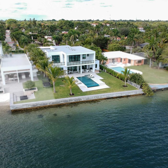 Luxury waterfront house with pool and lush garden.