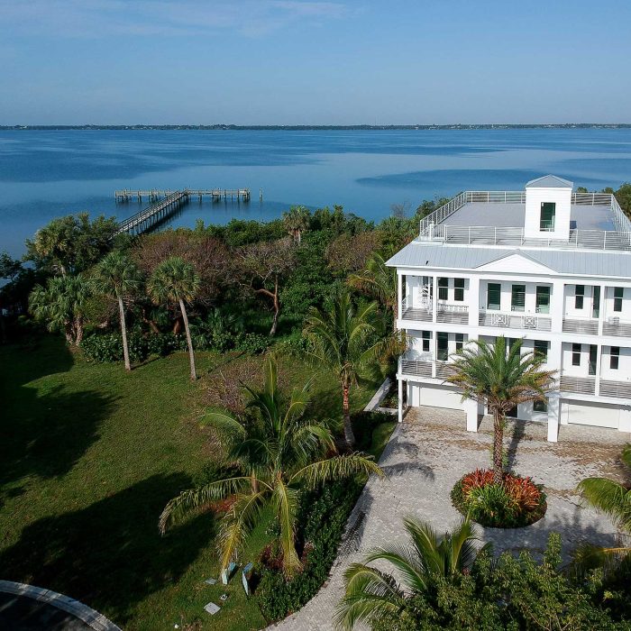 Waterfront house with tropical landscaping and pier view
