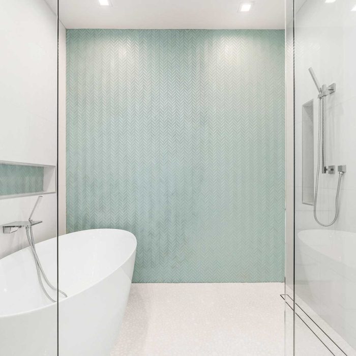 Modern bathroom with freestanding tub and teal accent wall.