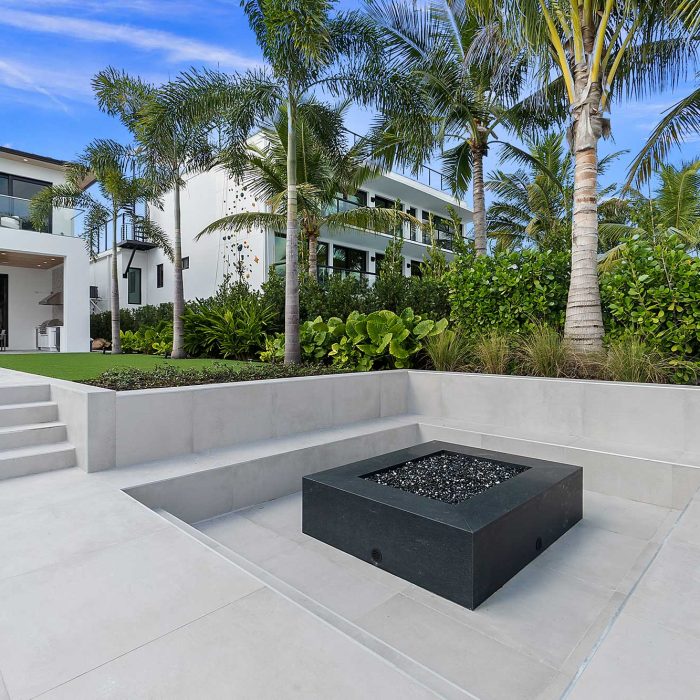 Luxury modern home with fire pit and palm trees.
