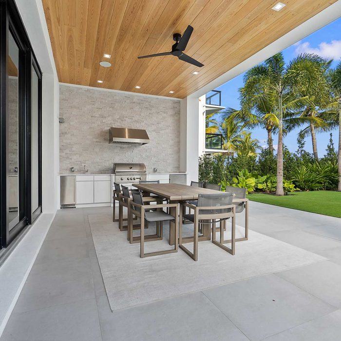 Modern outdoor patio with dining table and palm trees.