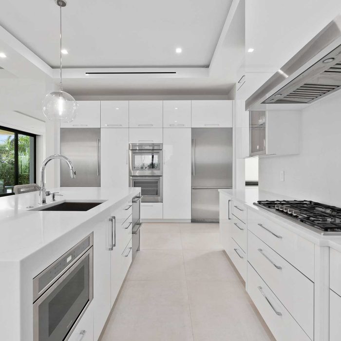 Modern white kitchen with island and appliances.