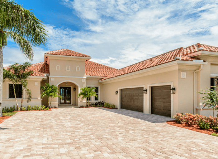 Luxury Mediterranean villa with palm trees and driveway.