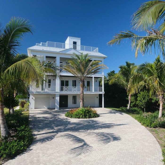 Tropical house with palm trees and sunny driveway.