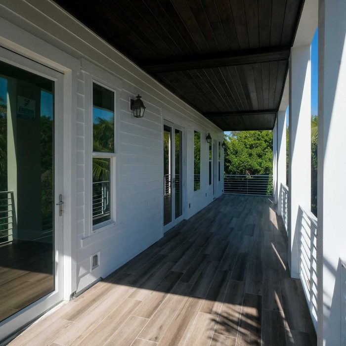 Modern wooden deck with glass doors and railings.