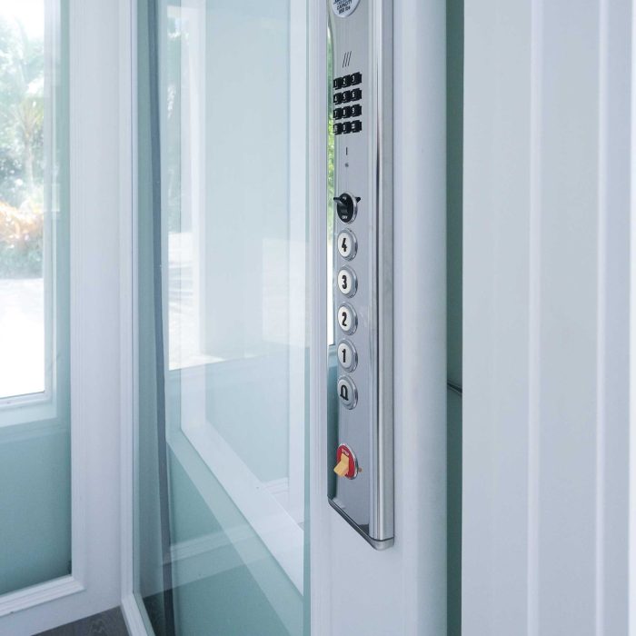 Modern elevator panel with numbered buttons and emergency switch.
