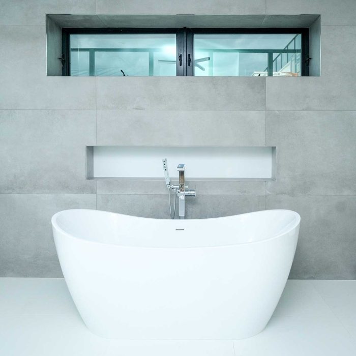 Modern bathroom with freestanding tub and window view.