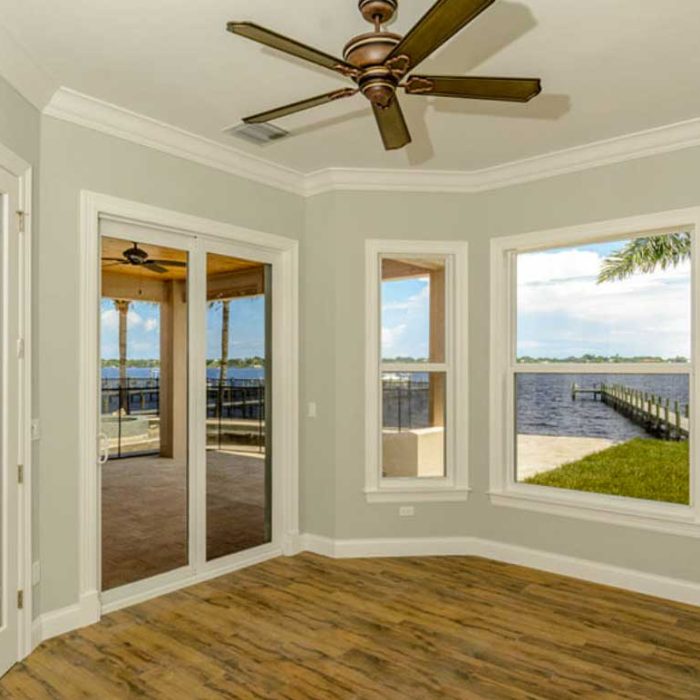 Bright room overlooking a lake with wooden floors.