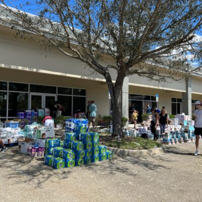 Volunteers distribute supplies outside a building.