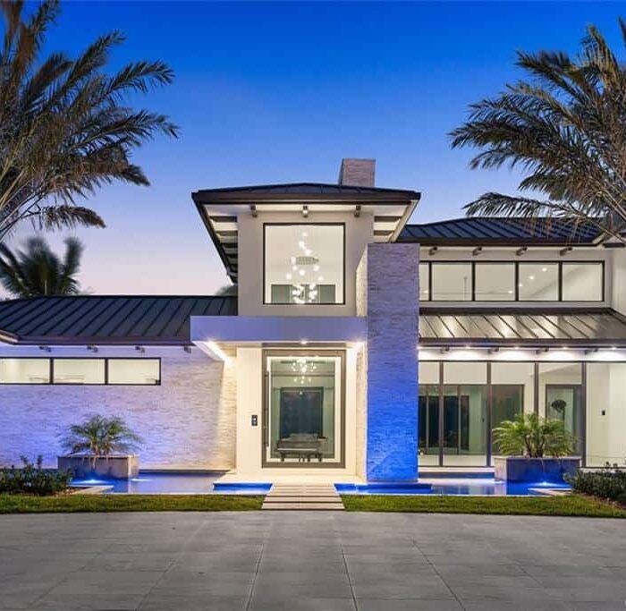 Modern luxury home exterior with palm trees at dusk.