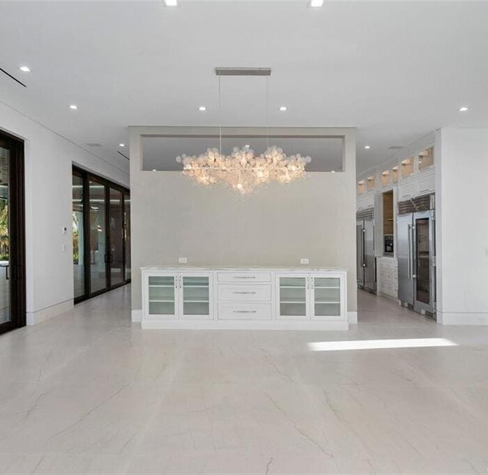 Spacious modern kitchen with large windows and chandelier.