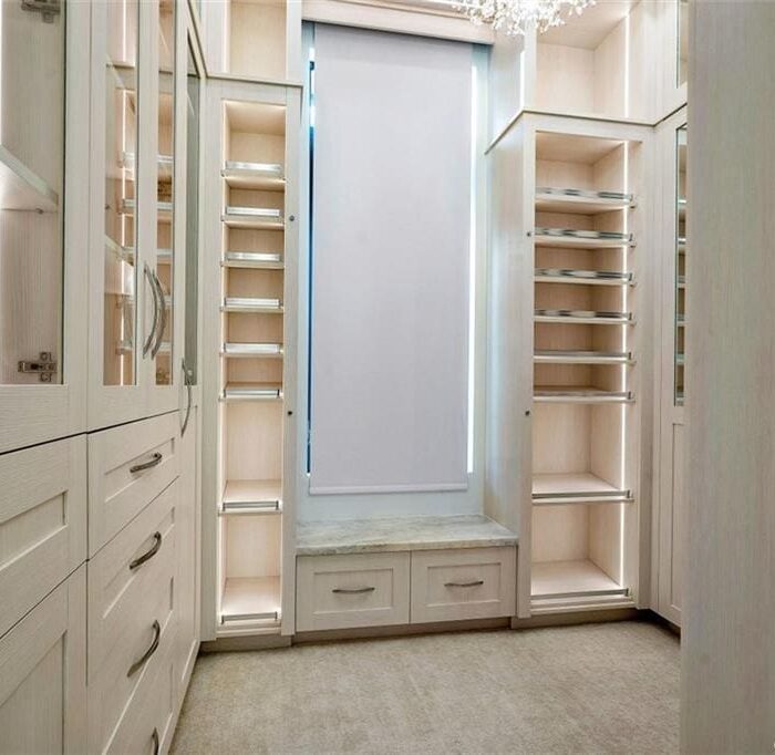 Spacious walk-in closet with white cabinetry and shelves.
