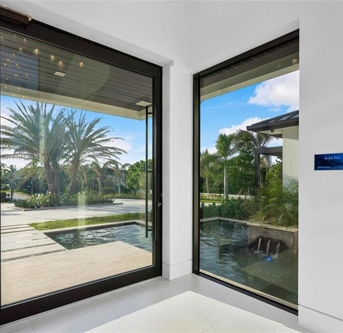 Modern entrance with glass walls and garden view.