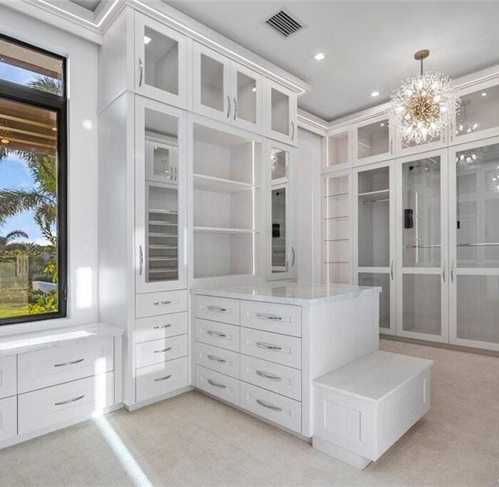 Luxurious white walk-in closet with chandelier.