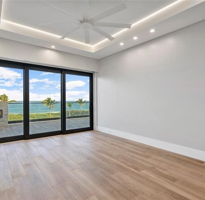 Empty room with ocean view through glass doors.