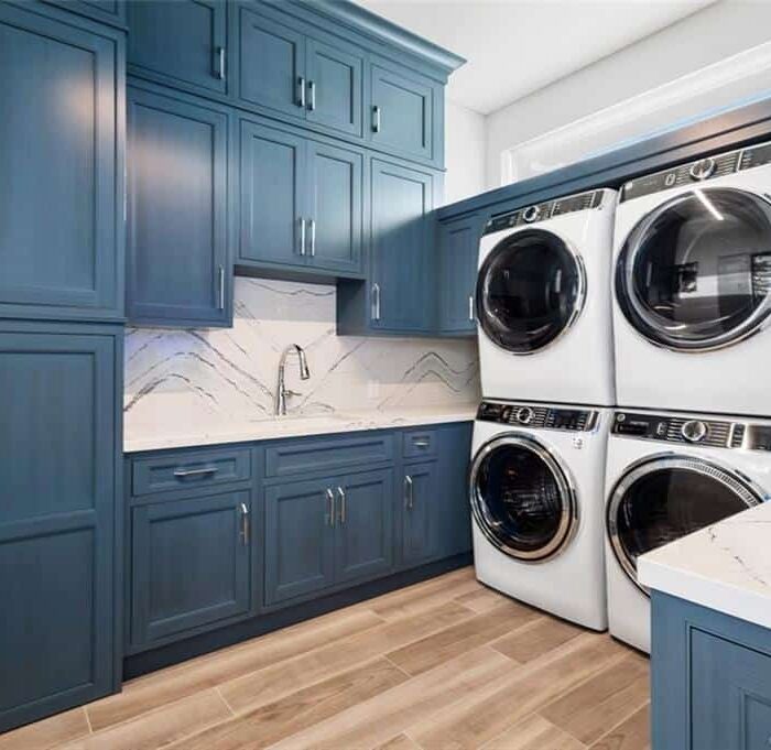 Modern laundry room with blue cabinets and appliances.