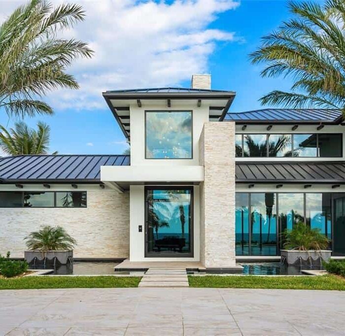Modern beachfront house with palm trees.