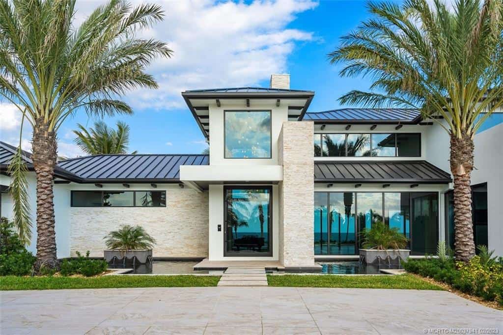Modern beachfront house with palm trees.