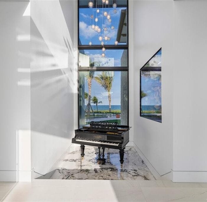 Grand piano in bright ocean-view hallway.
