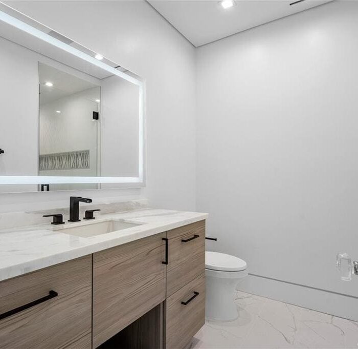 Modern bathroom with wooden vanity and large mirror.