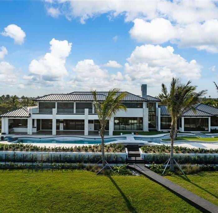 Modern mansion with pool and palm trees.