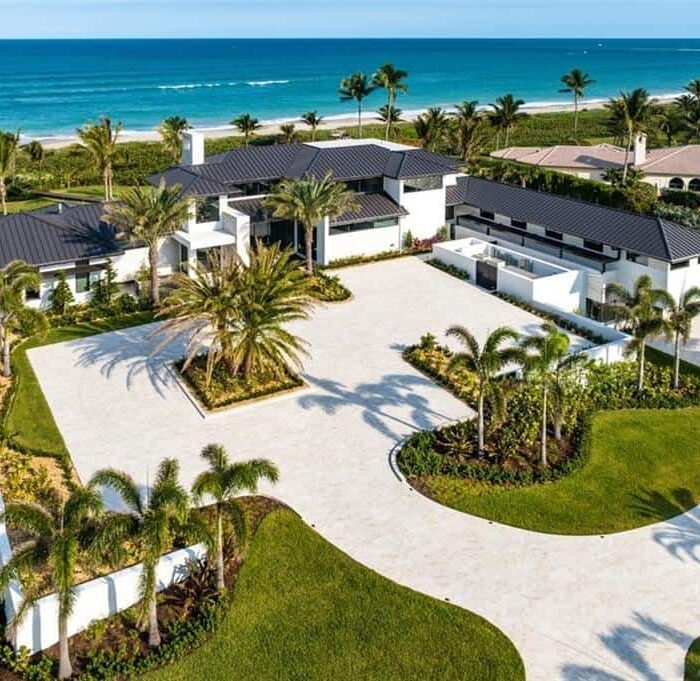Luxury beachfront villa with ocean view and palm trees.
