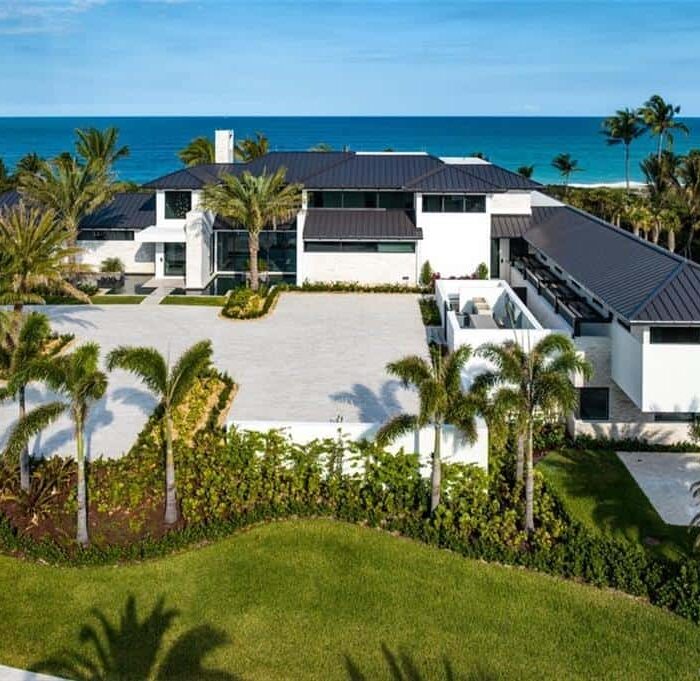 Luxury beachfront mansion with palm trees and ocean view.
