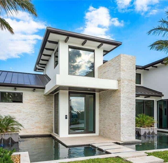 Modern home with glass windows and palm trees.