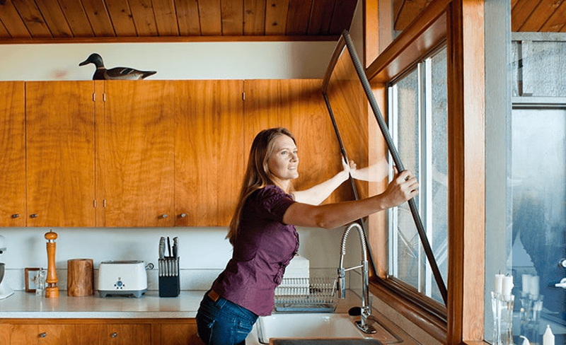 Woman opening kitchen window for fresh air