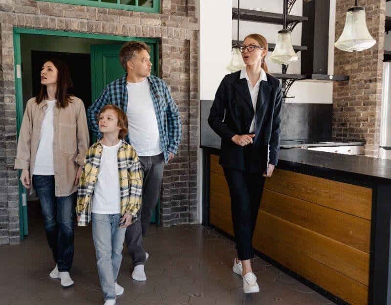 Family touring a modern kitchen with real estate agent.