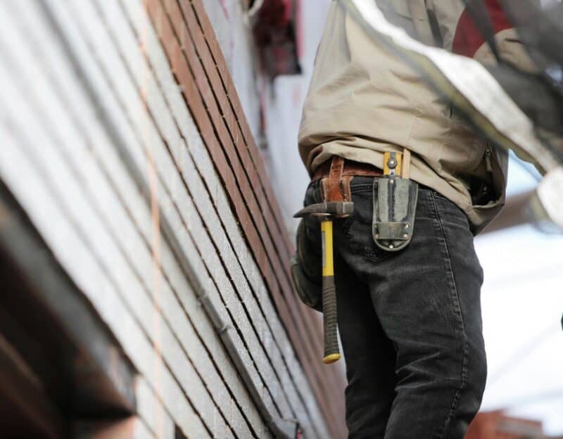 Construction worker with tool belt near stacked bricks.