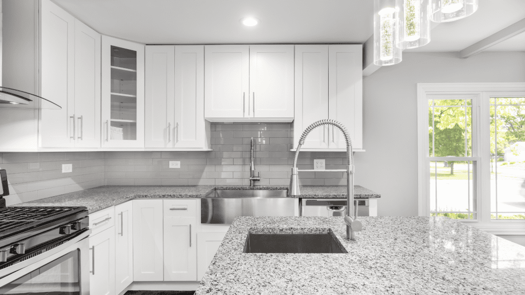 Modern kitchen with granite countertops and white cabinets.