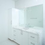 Modern white bathroom with large mirror and sink.