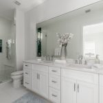Modern white bathroom with double sinks and shower.