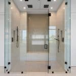 Modern glass shower with dual showerheads and tile design.