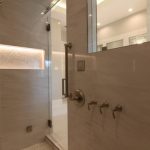 Modern shower with glass door and chrome fixtures.