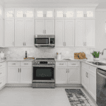 Modern white kitchen with stainless steel appliances.