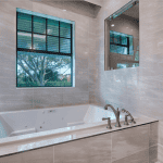 Modern bathroom with large bathtub and window view.