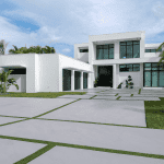 Modern white house with large windows and driveway.
