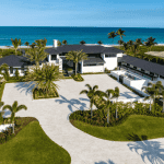 Luxury beachfront mansion with palm trees and ocean view.