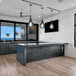 Modern kitchen with ocean view and pendant lights.