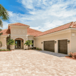 Mediterranean-style house with palm trees and driveway.