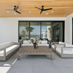 Modern patio with white sofas and wooden table.