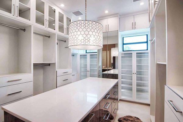 Spacious modern walk-in closet with white cabinetry.